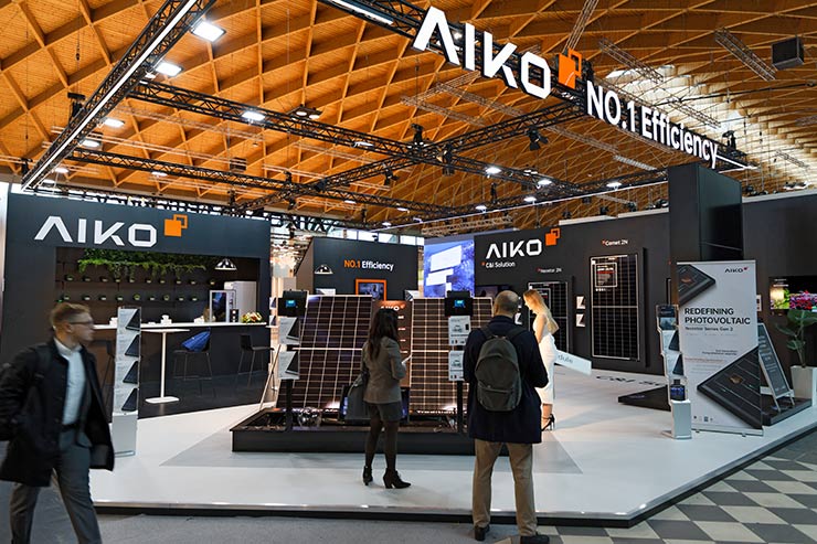 Stand espositivo AIKO con pannelli solari ad alta efficienza, visitatori osservano la tecnologia resistente all'ombreggiamento in fiera